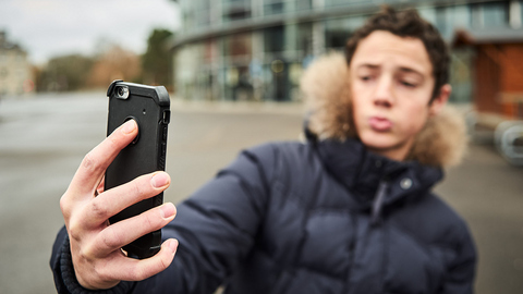Teenager posiert vor Smartphone-Kamera. 