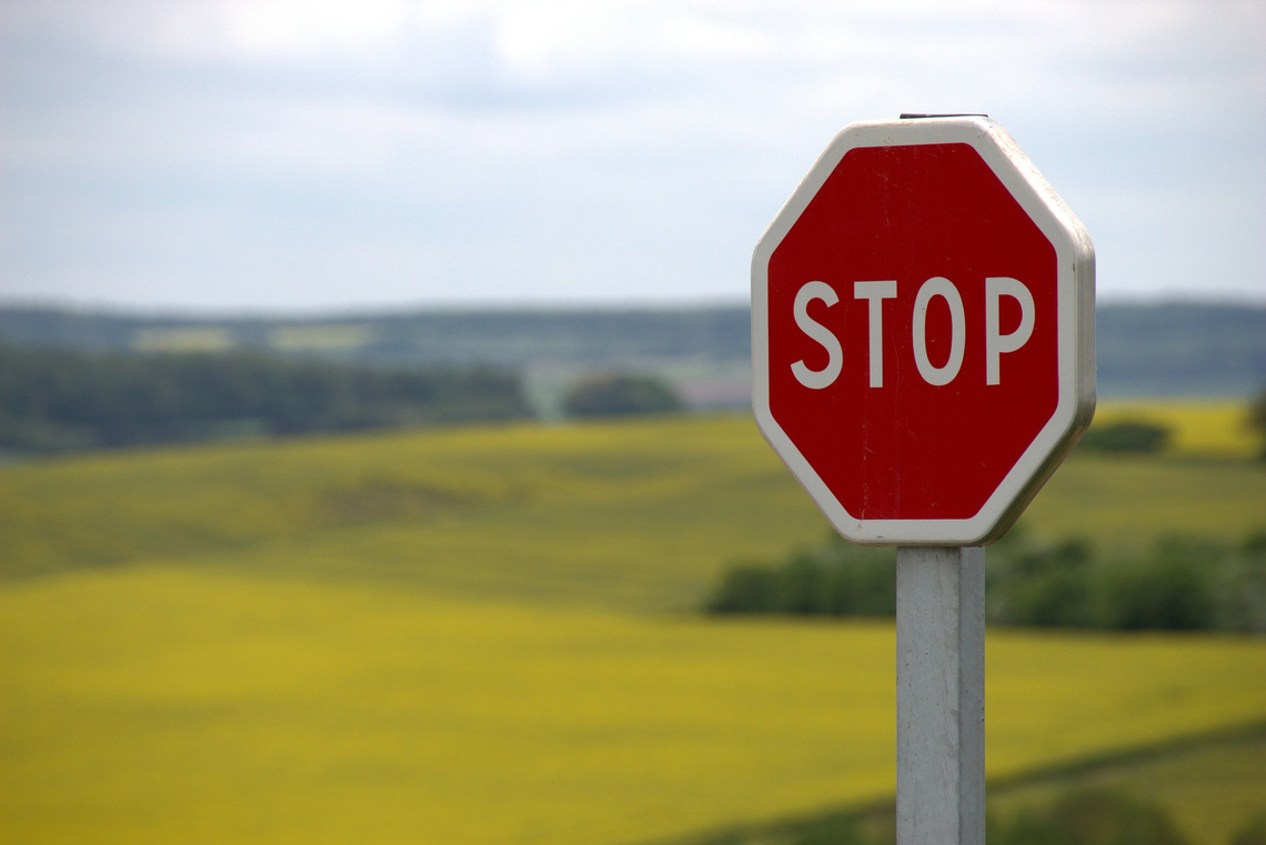 Stop-Verkehrszeichen, im Hintergrund sieht man etwas unscharf eine ebene Landschaft.