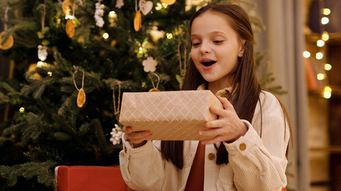 Mädchen mit Geschenk unter dem Weihnachtsbaum