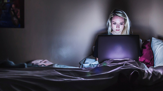 Mädchen sitz im Dunkeln am Computer