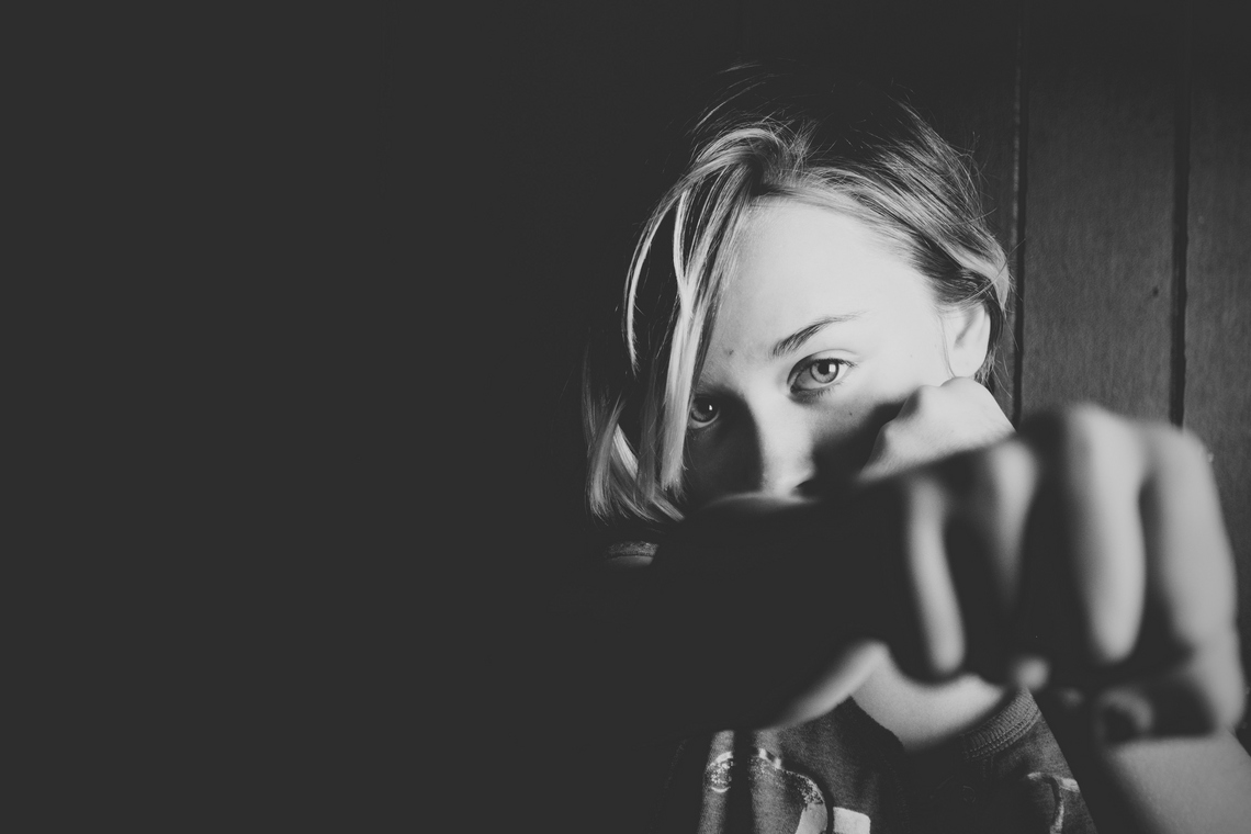 Schwarzweiß-Foto von einer Frau, die mit ihrer geballten Faust in Richtung Kamera schlägt.
