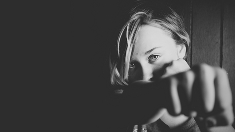 Schwarzweiß-Foto von einer Frau, die mit ihrer geballten Faust in Richtung Kamera schlägt.