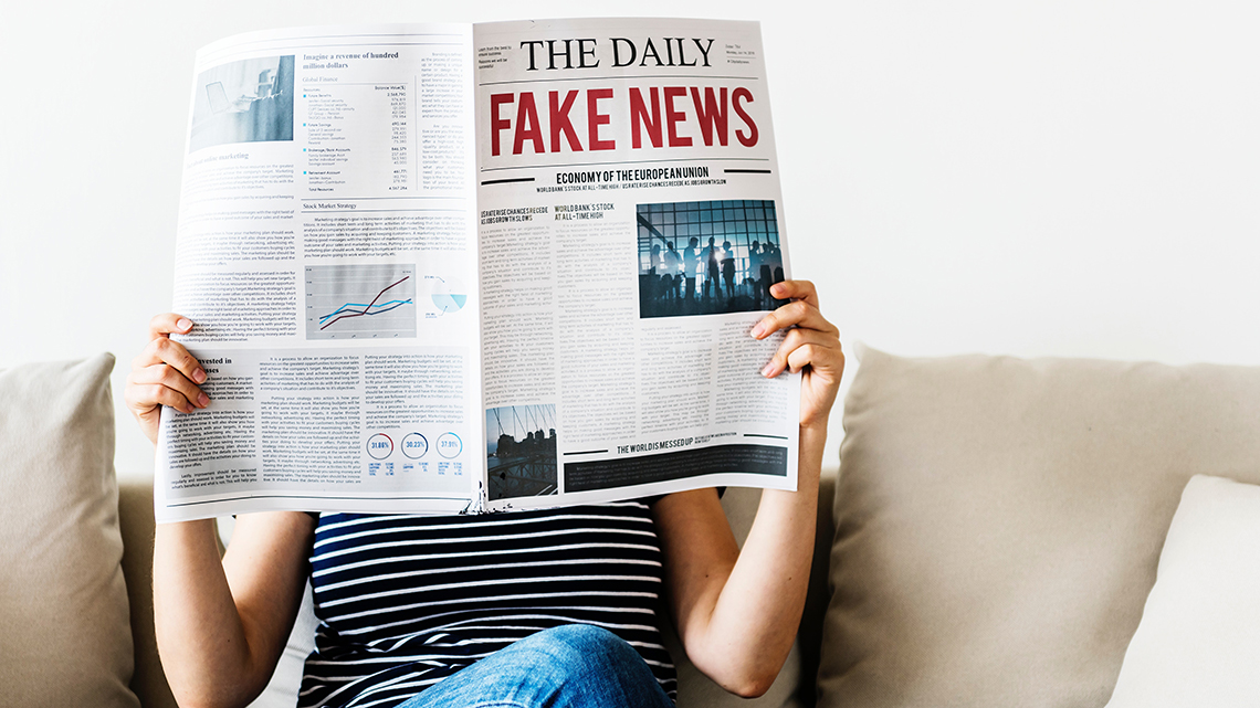 Person liest eine Zeitung mit dem Titel Fake News