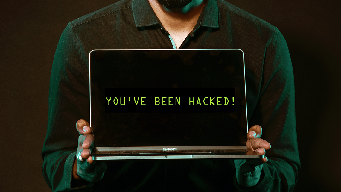 Person hält Laptop in den Händen. Auf dem Bildschirm steht "You've been hacked!"