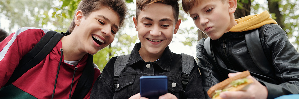 drei Jungs schauen in ein Smartphone